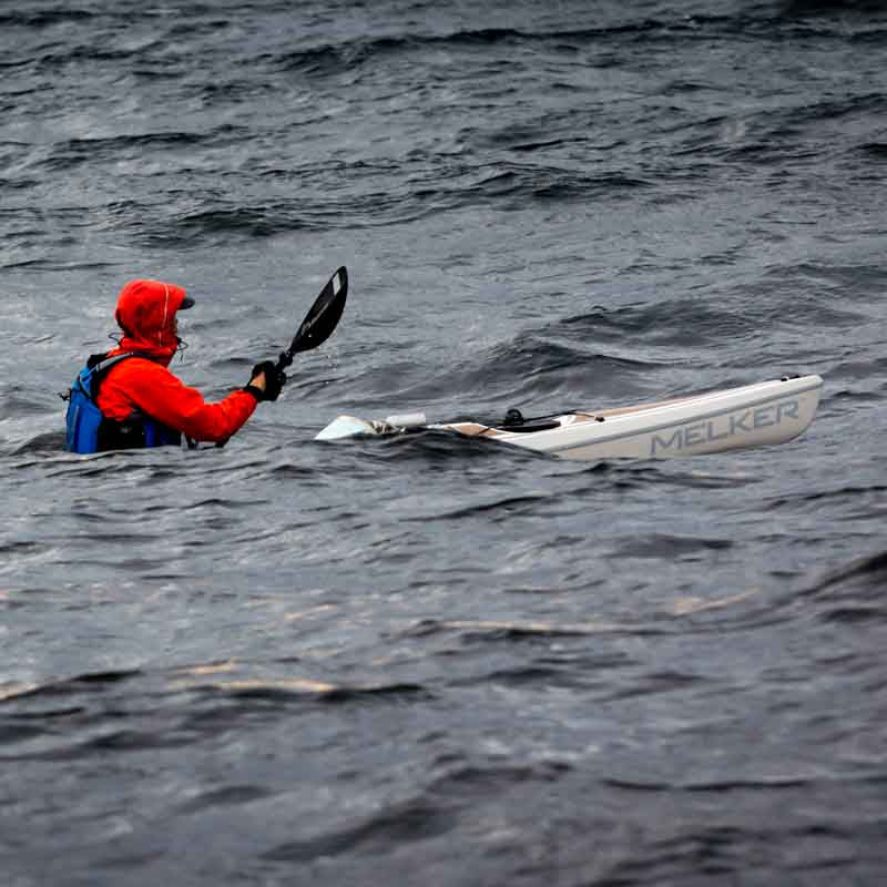 Person paddling a kayak in waves